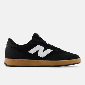 Black low-top sneaker in suede with a white 'N' logo and a tan gum sole, side view.